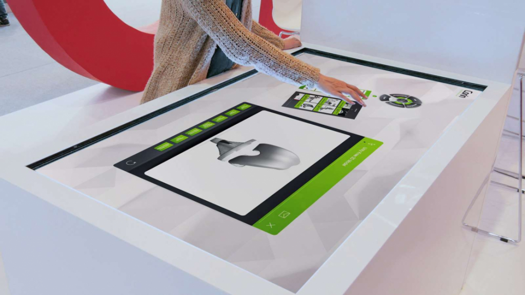 woman interacting with Corin interactive touchscreen software displayed on large white table