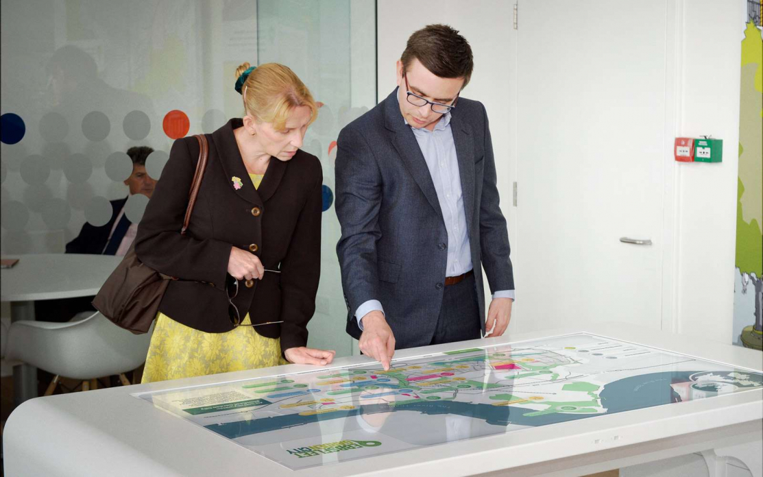 woman and man interacting with Ebbsfleet interactive touchscreen display on white table