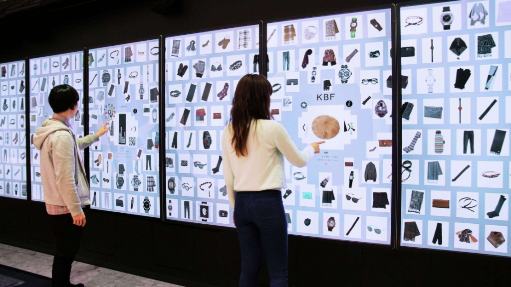two people amongst several large monitors interacting with touchscreen informationwall
