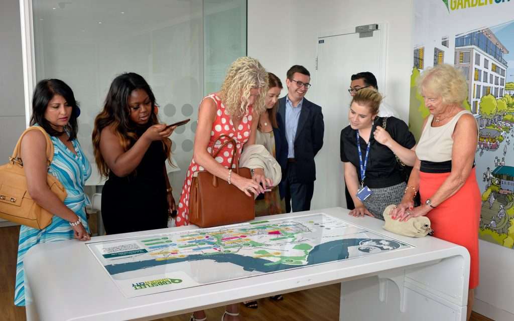 group of people interacting with ebbsfleet touchscreen display on white table in office