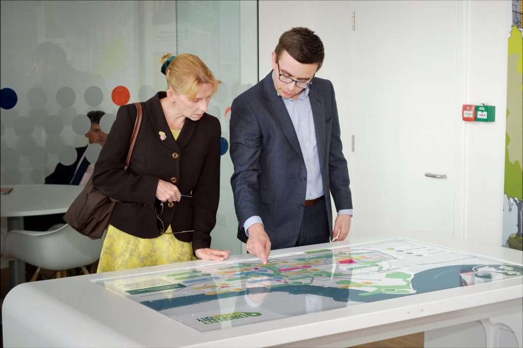 woman and man interacting with ebbsfleet interactive touchscreen display on white table