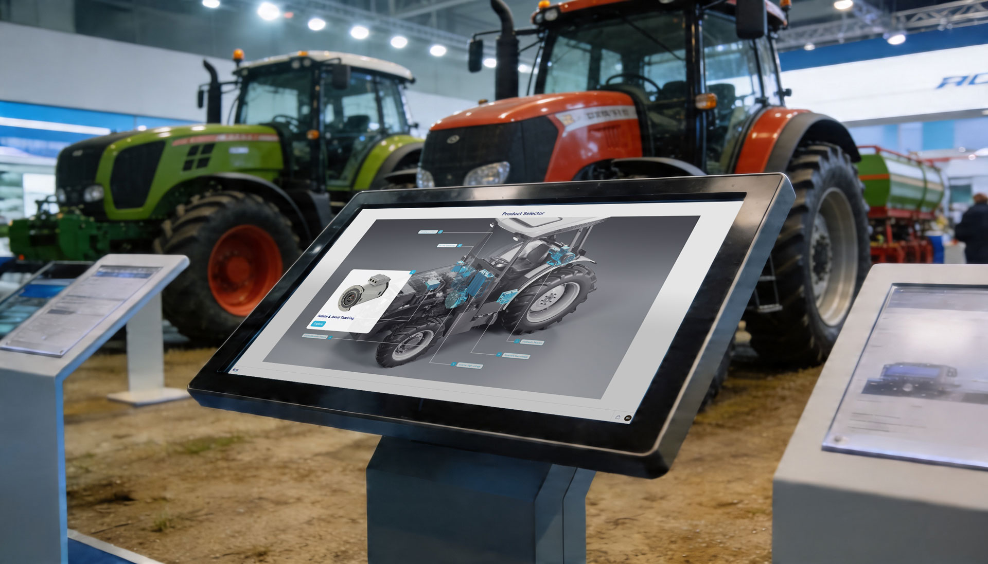 Freestanding touchscreen kiosk on an exhibition stand running an interactive product selector, with an exploded 3D tractor model and highlighted components, real tractors displayed behind it.